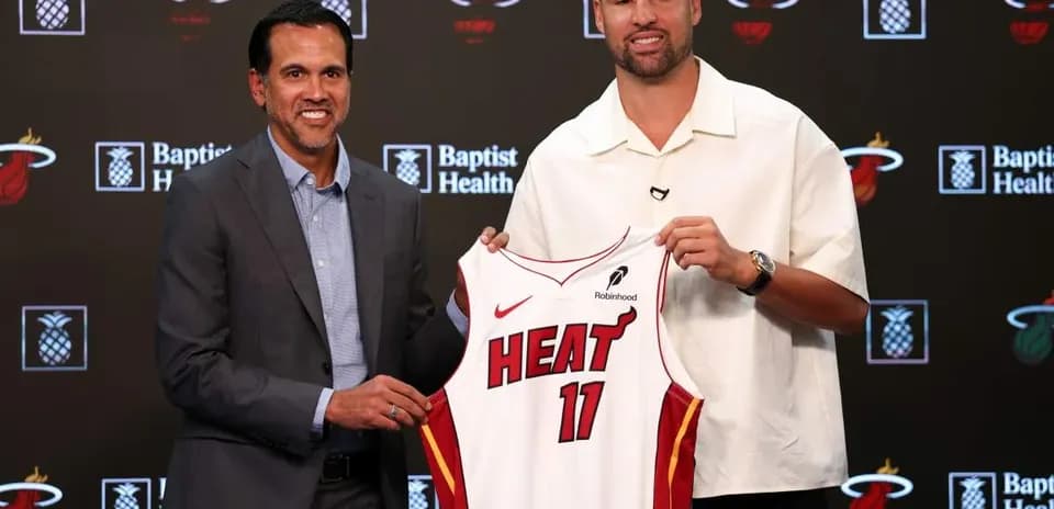 Coach and player holding Miami Heat jersey at event