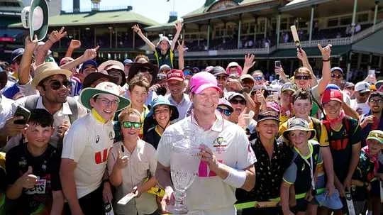 Cricketer celebrating with fans holding trophy