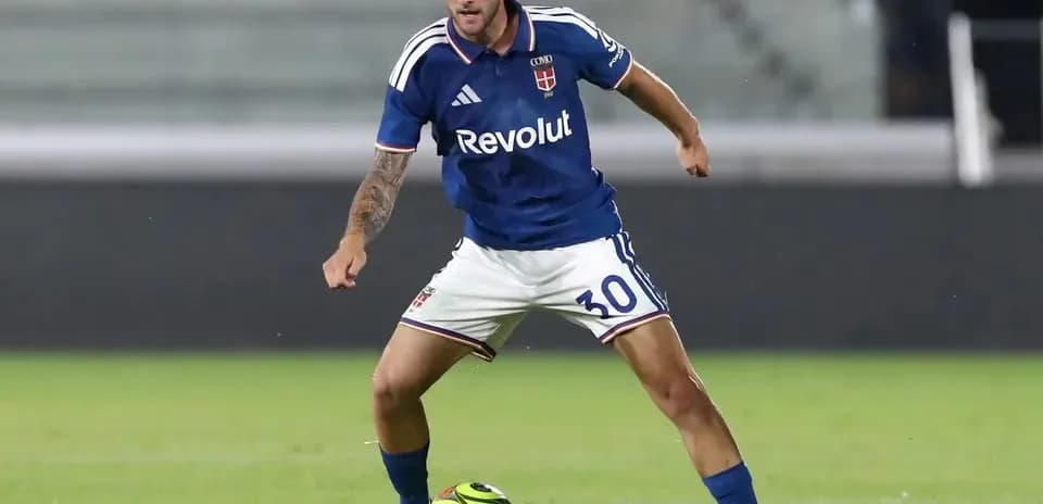 Player in blue kit dribbling soccer ball on field