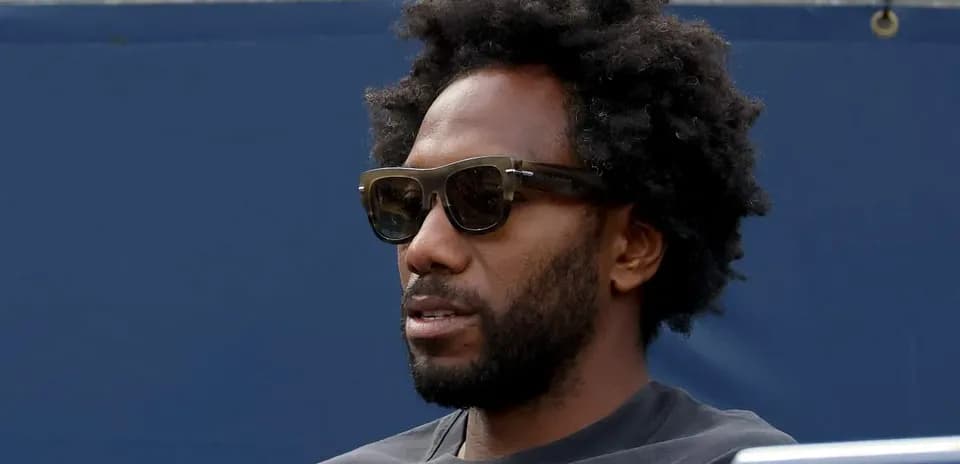 Person wearing sunglasses sitting in a stadium