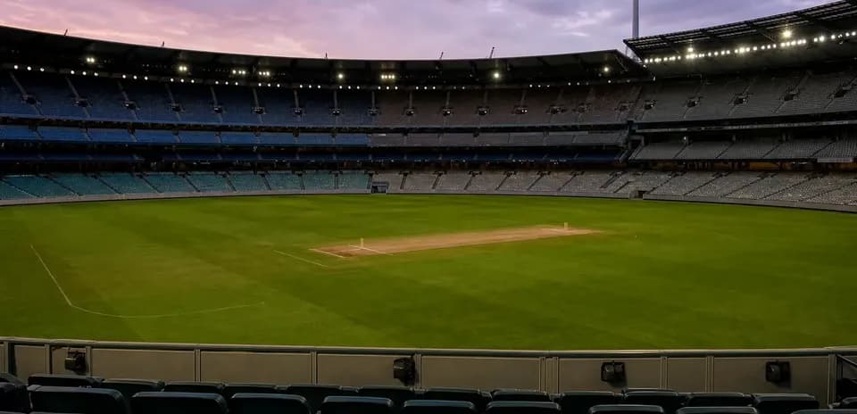 Empty cricket stadium with grass pitch and lights