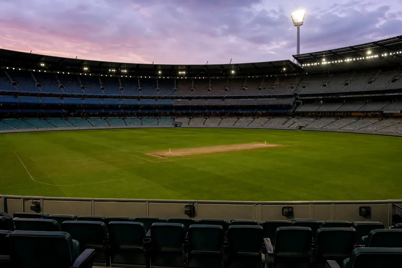 Empty cricket stadium with grass pitch and lights