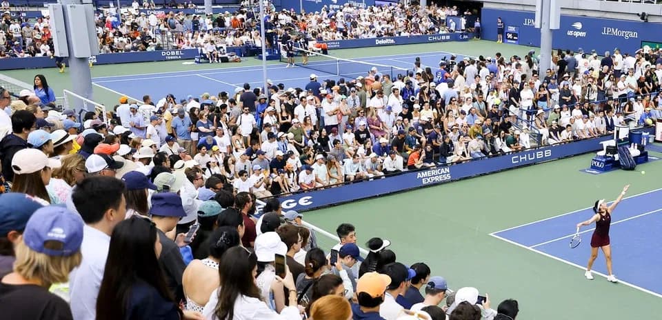 Tennis player serving to large crowd at match