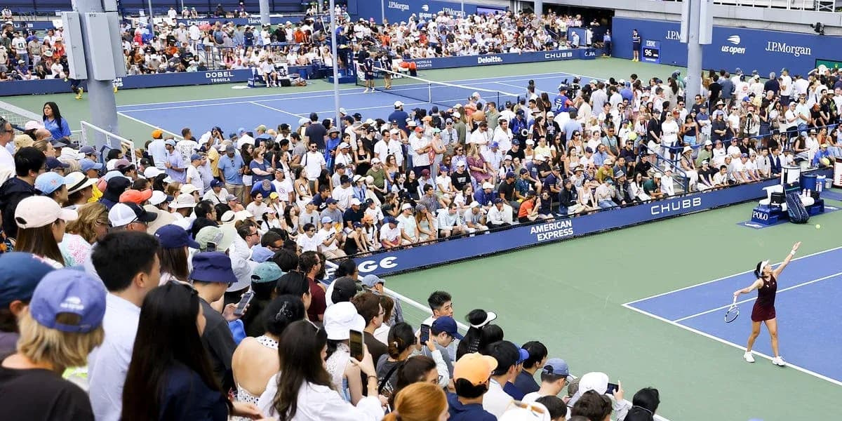 Tennis player serving to large crowd at match