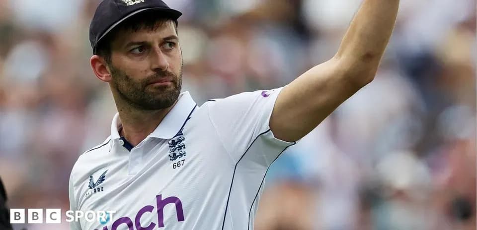 Cricketer celebrating with raised hand in white uniform