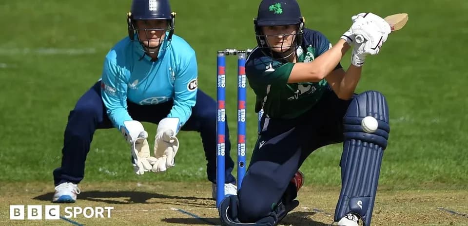 Batter playing a shot while wicketkeeper watches