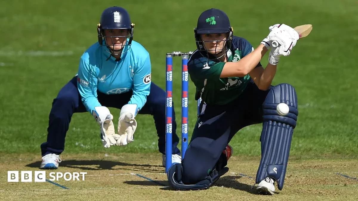 Batter playing a shot while wicketkeeper watches