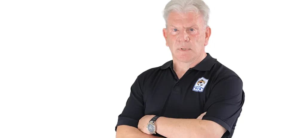 Coach standing with arms crossed, serious expression