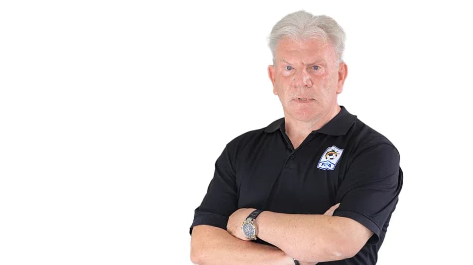 Coach standing with arms crossed, serious expression
