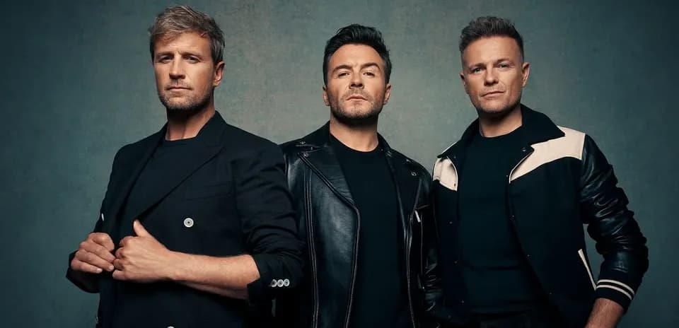 Three men posing in stylish outfits against a backdrop