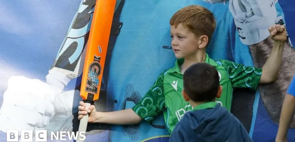 Child posing with cricket bat and poster backdrop