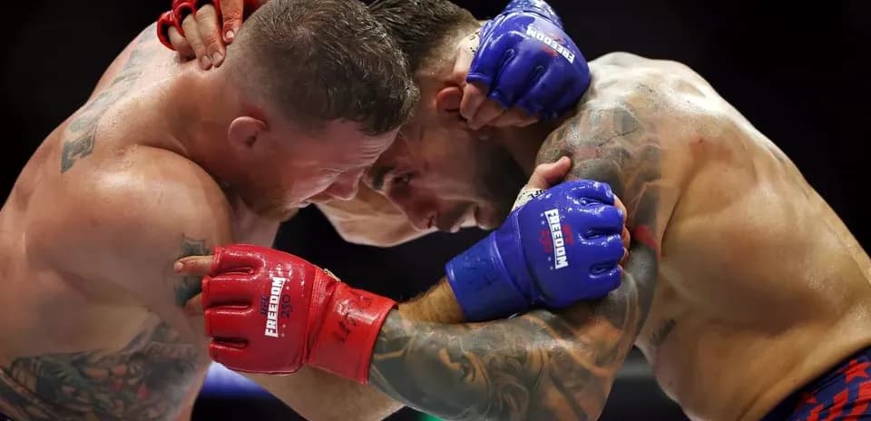 Two fighters clinching during a match in the ring