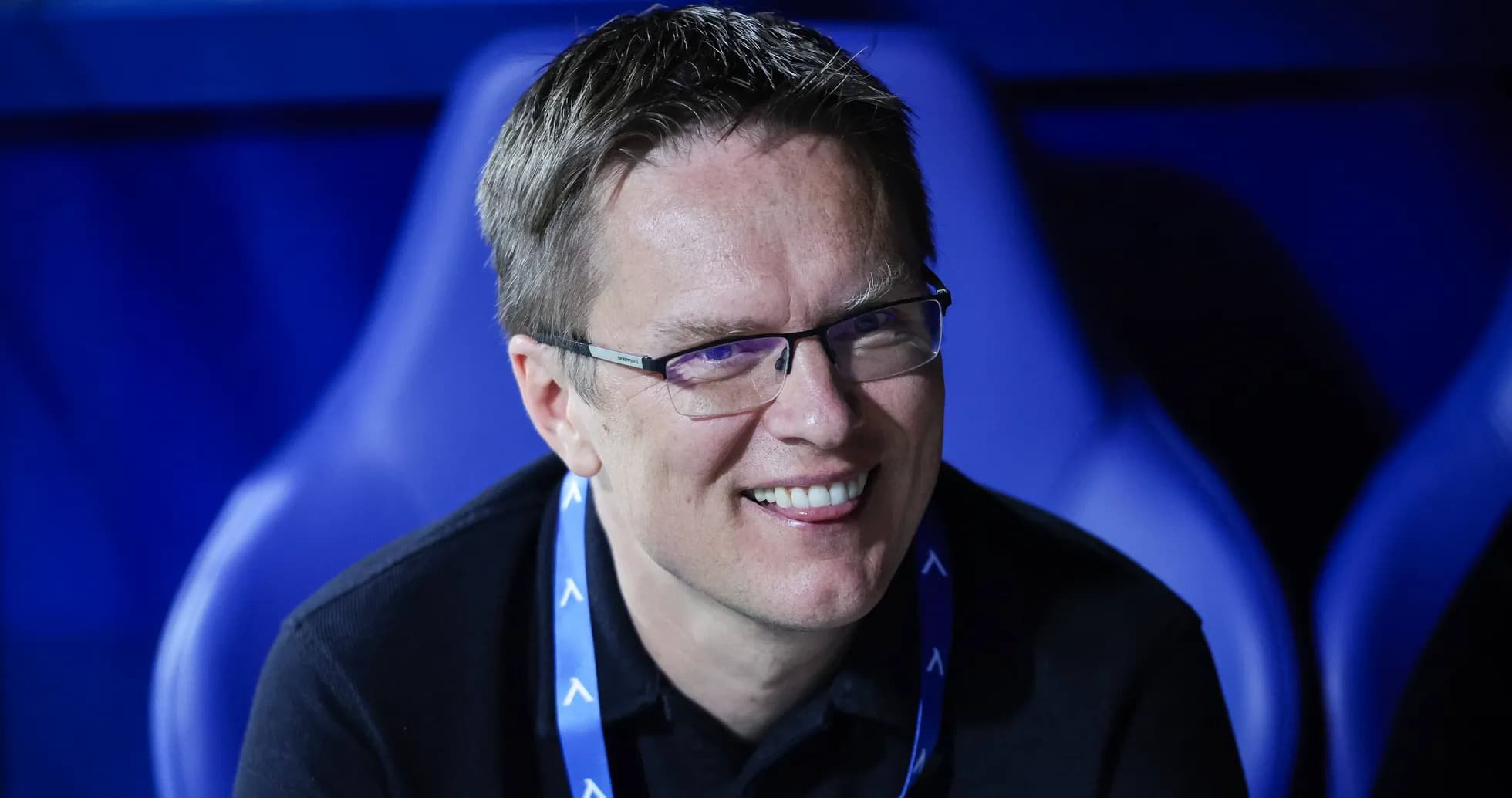 Man smiling while seated in stadium environment
