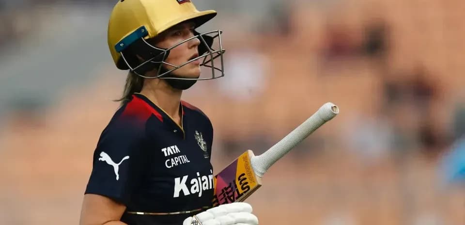 Cricketer walking off field with bat in hand