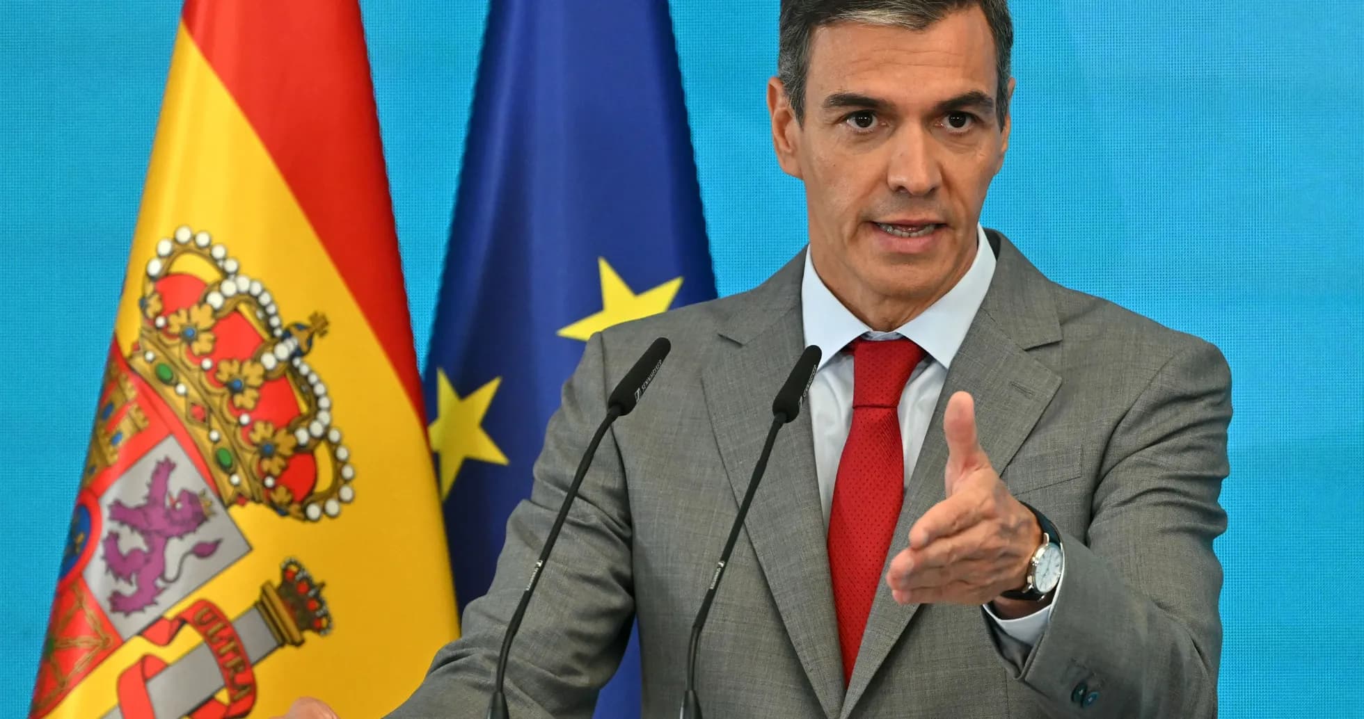 Man speaking at podium with Spanish and EU flags