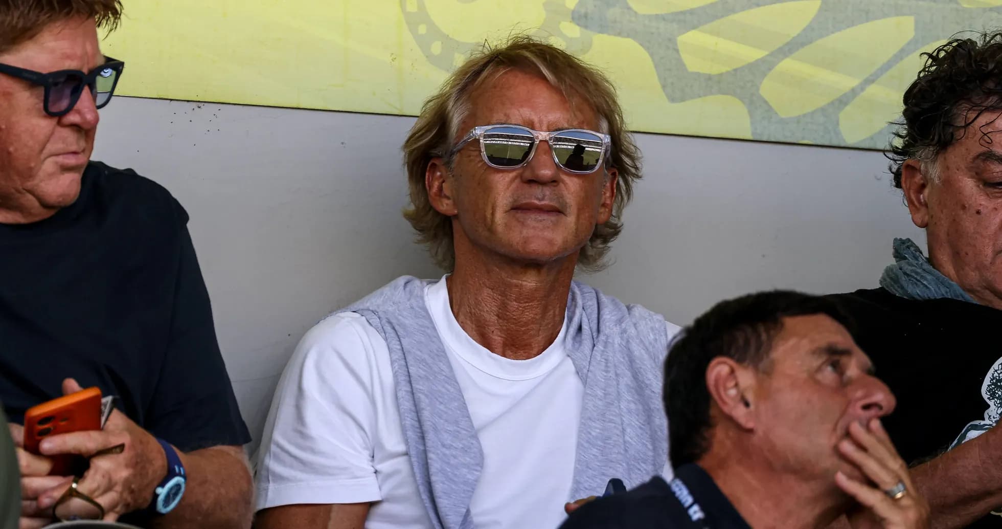 Man wearing sunglasses seated among others