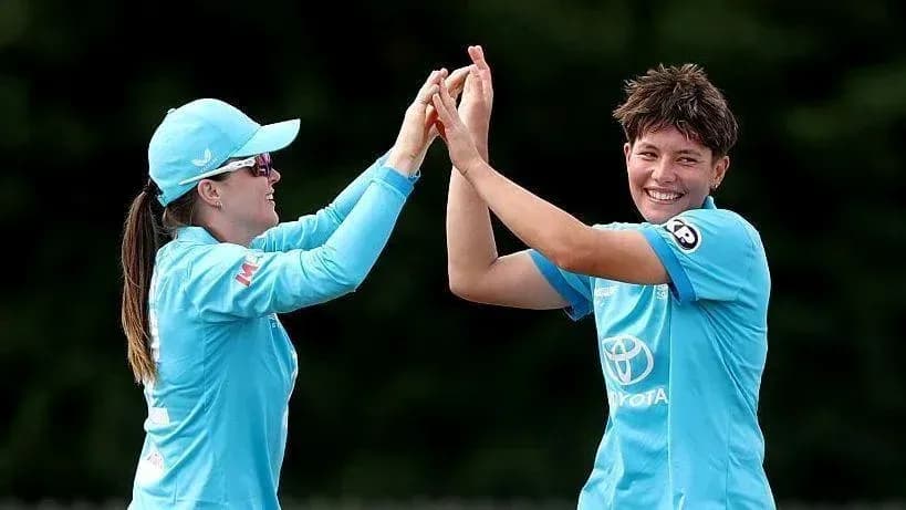 Two cricket players celebrating with high fives