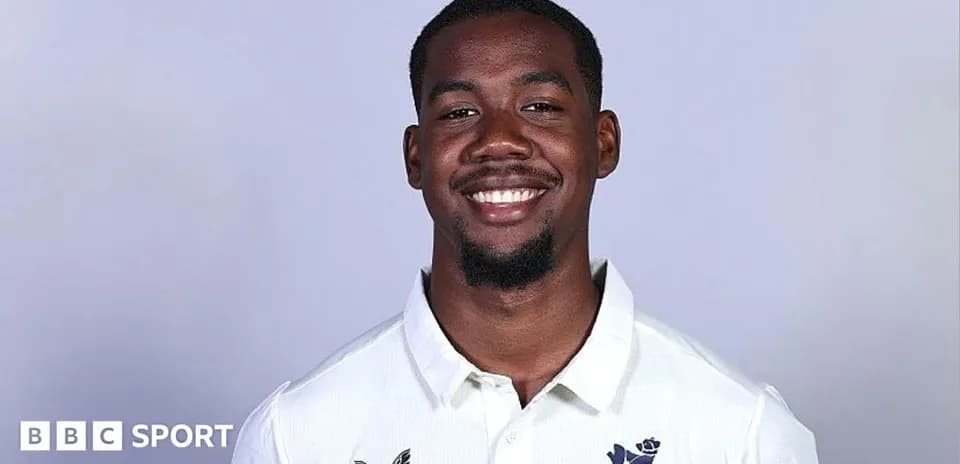 Smiling cricketer wearing a white team shirt
