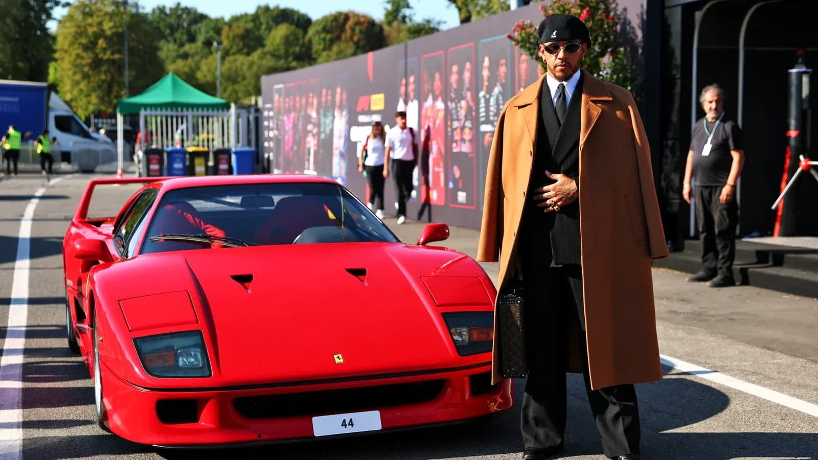 Person in stylish outfit next to red sports car