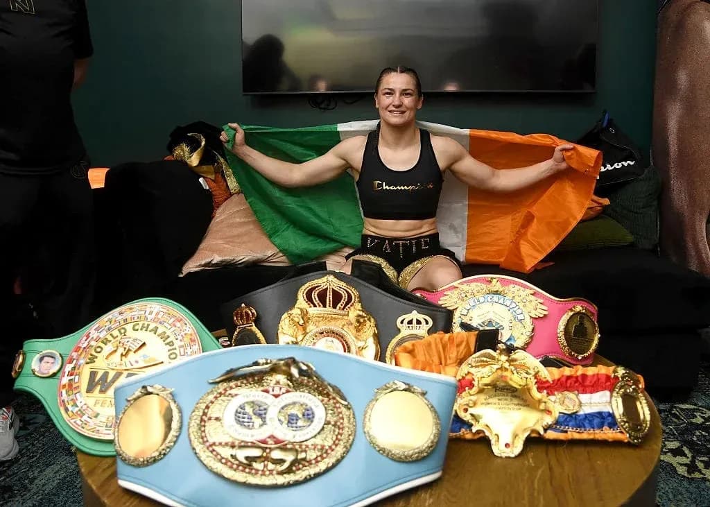 Female boxer holding Irish flag with championship belts