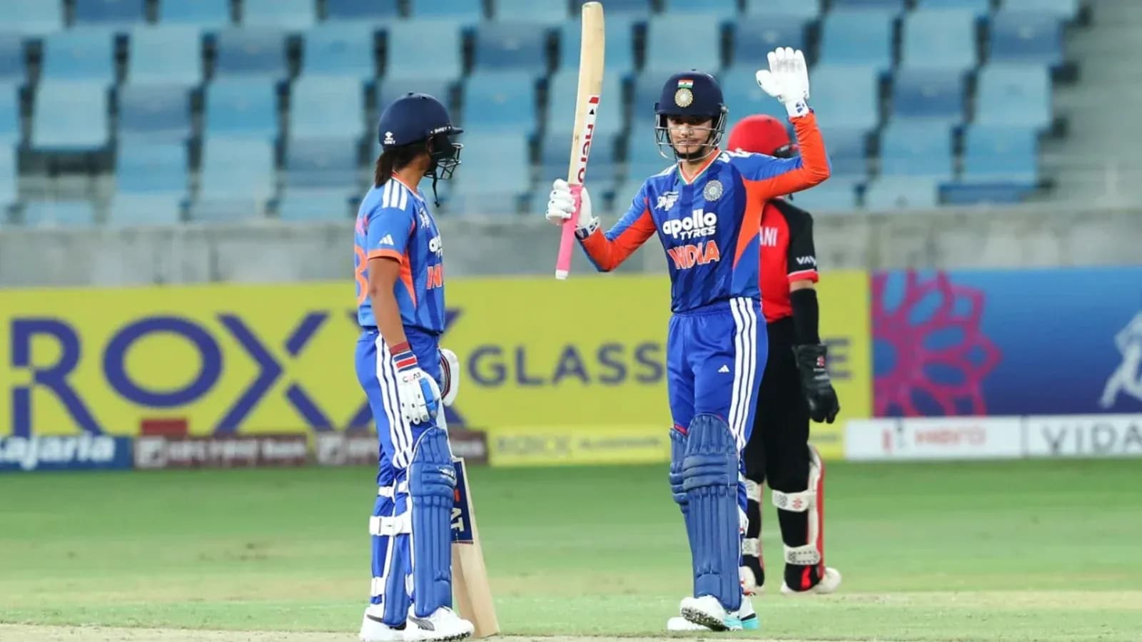 Batsman celebrating while teammate looks on during match