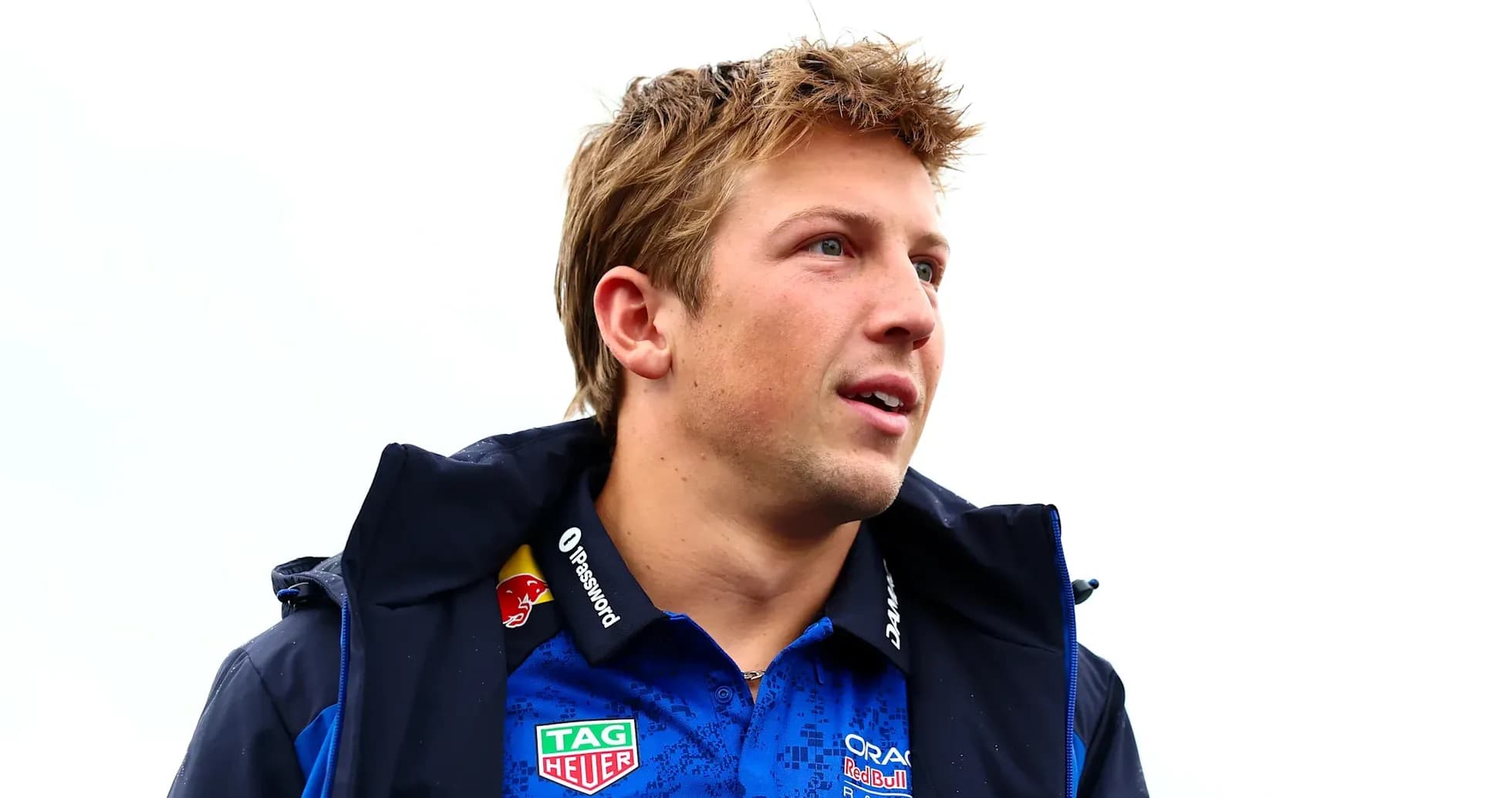 Driver wearing team jacket and shirt, looking off-camera