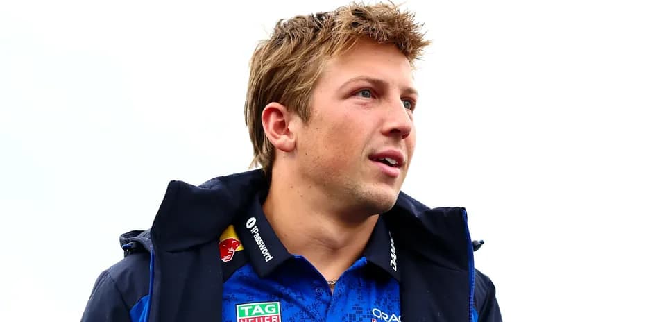 Driver wearing team jacket and shirt, looking off-camera