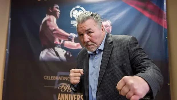 Former boxer posing with fists at event backdrop