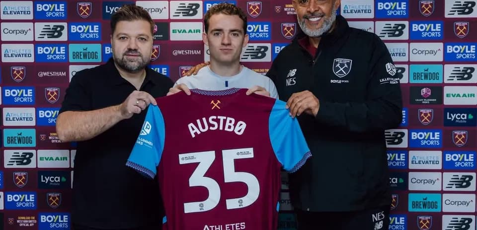 Player holding jersey with staff at signing event