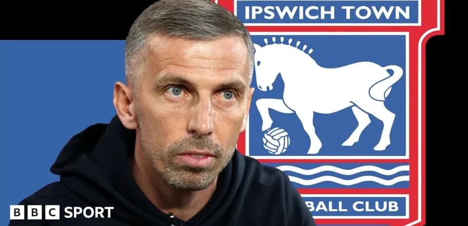 Manager speaking with Ipswich Town logo in background