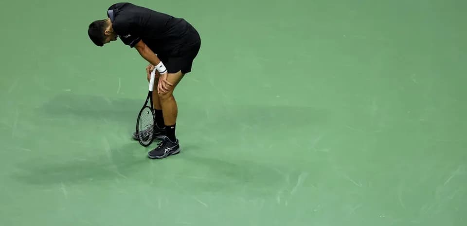 Tennis player bending over with racket on court