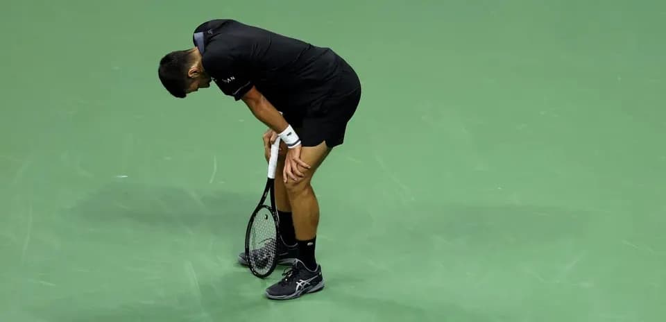 Tennis player bent over holding racket on court