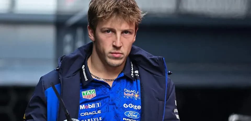 Driver wearing team jacket, holding a drink