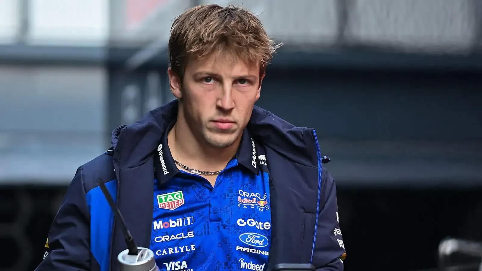 Driver wearing team jacket, holding a drink