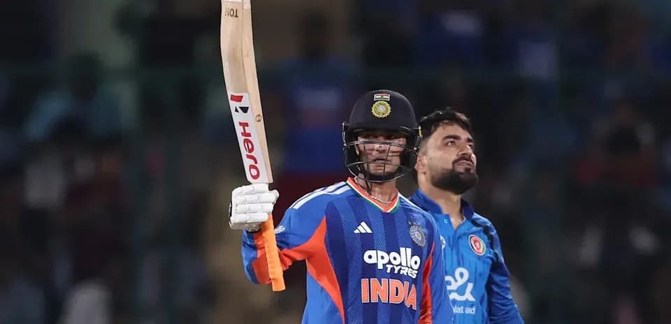 Batsman celebrating century with raised bat during match