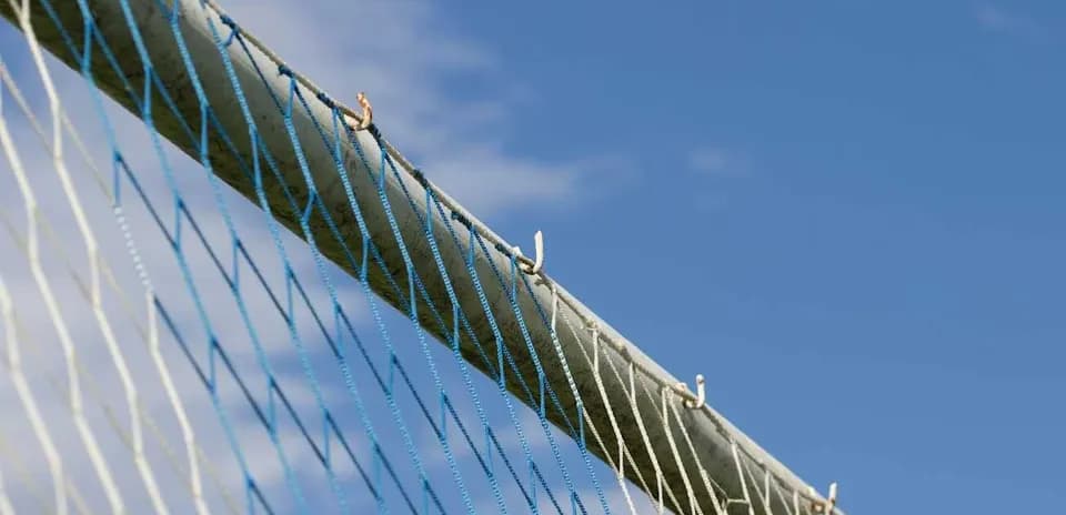 Close-up of a sports goal netting against blue sky