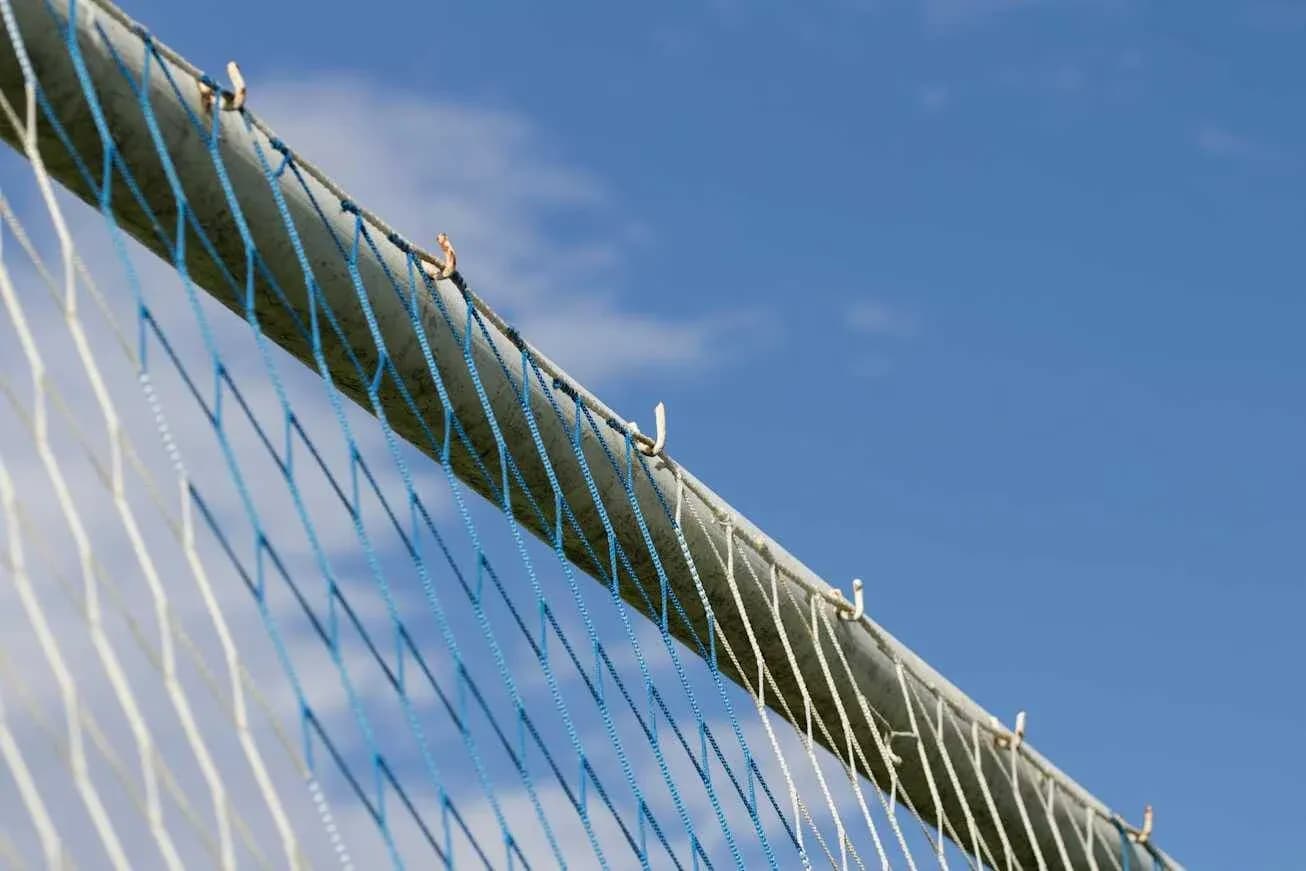 Close-up of a sports goal netting against blue sky