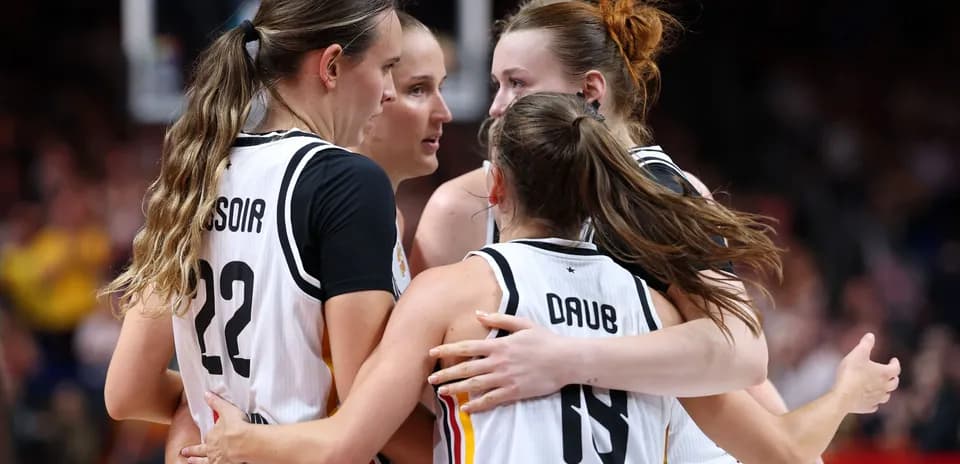 Four basketball players celebrating in a huddle