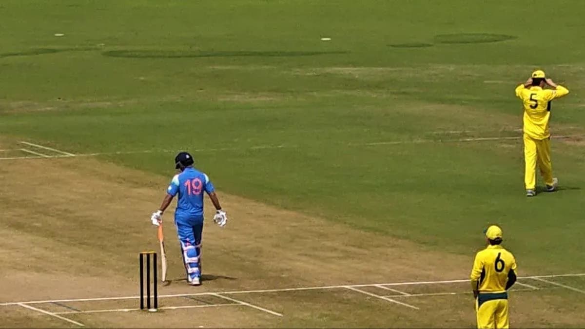 Batsman in blue uniform walking towards the wicket