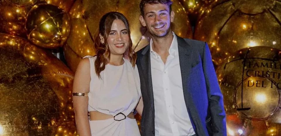 Two people posing together in front of golden decorations