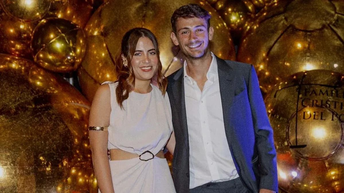 Two people posing together in front of golden decorations