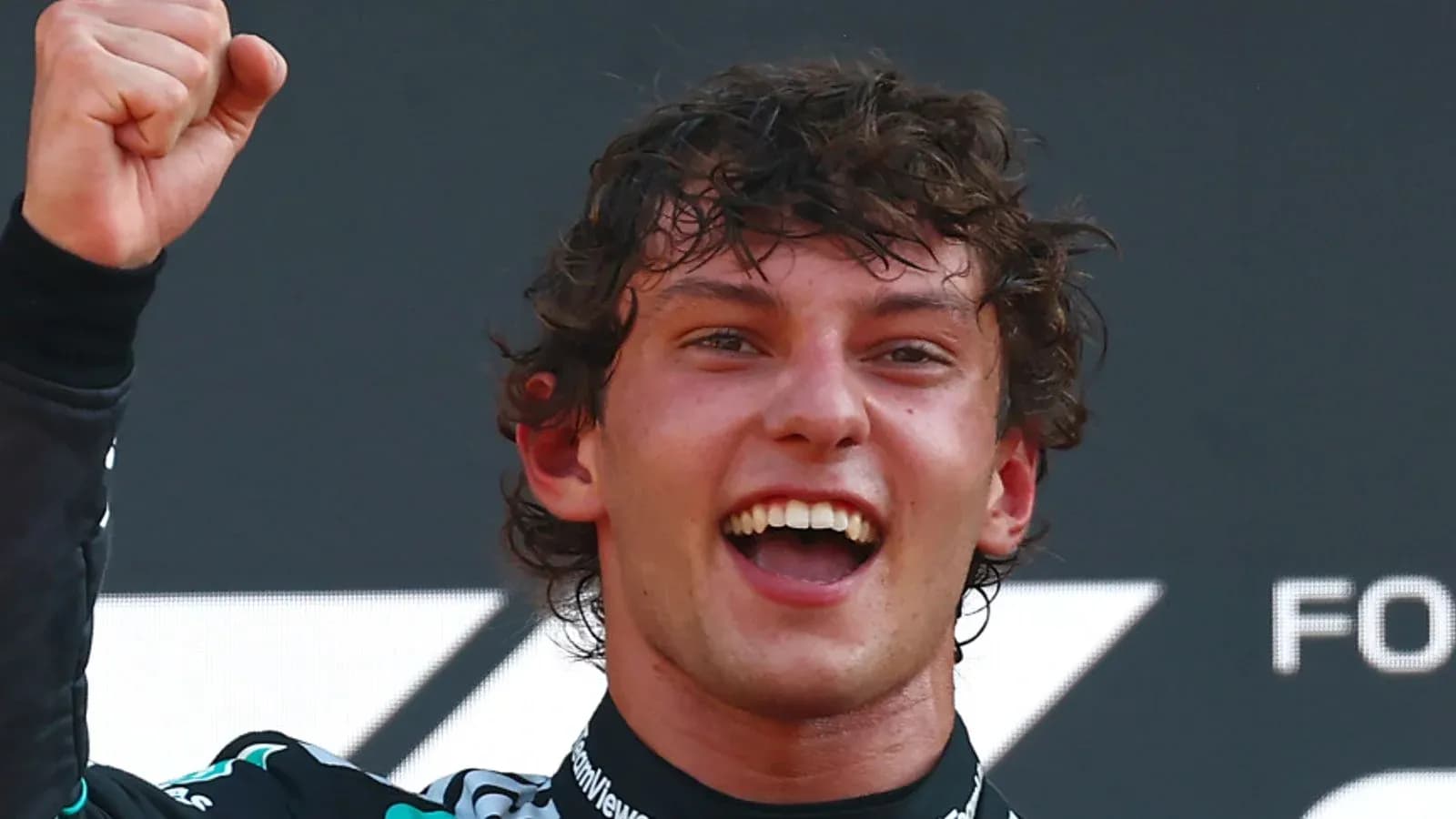 Driver celebrating victory with raised fist on podium