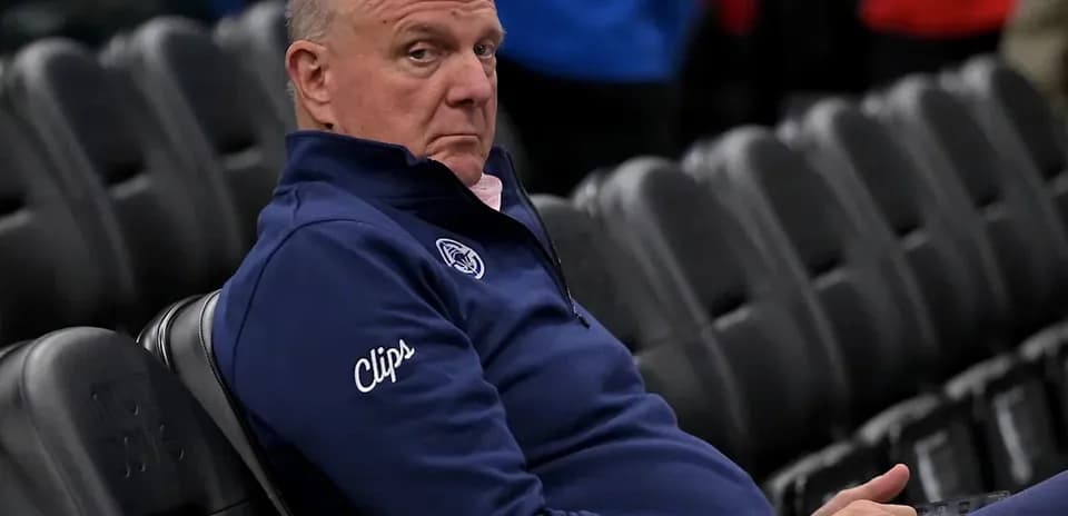 Man seated in empty arena wearing Clippers jacket