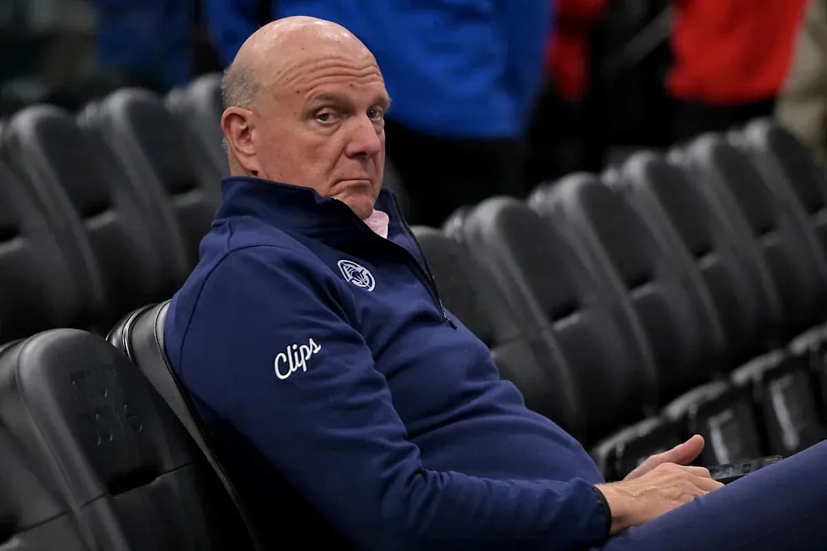 Man seated in empty arena wearing Clippers jacket