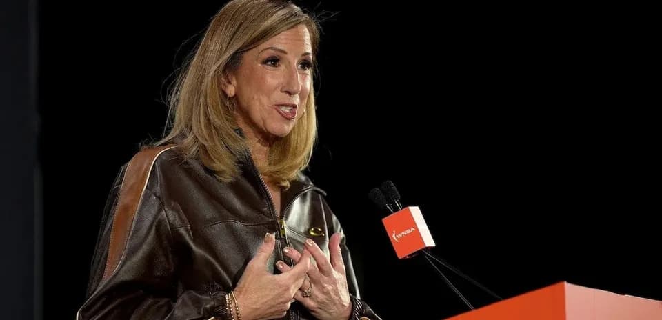 Woman speaking at podium with WNBA branding