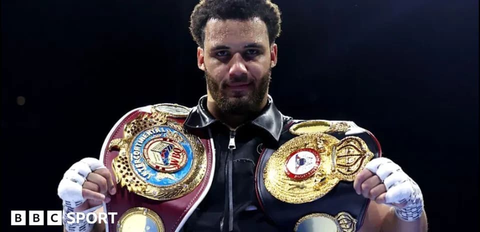Boxer holding two championship belts in the ring