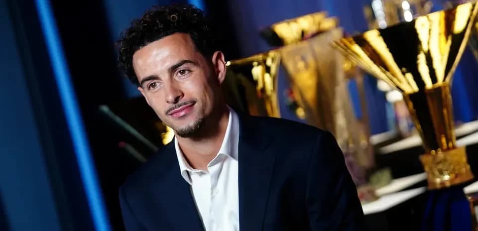 Man in suit with trophies in background