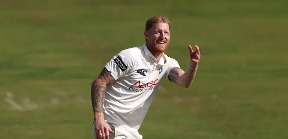 Cricketer fielding the ball on grass pitch