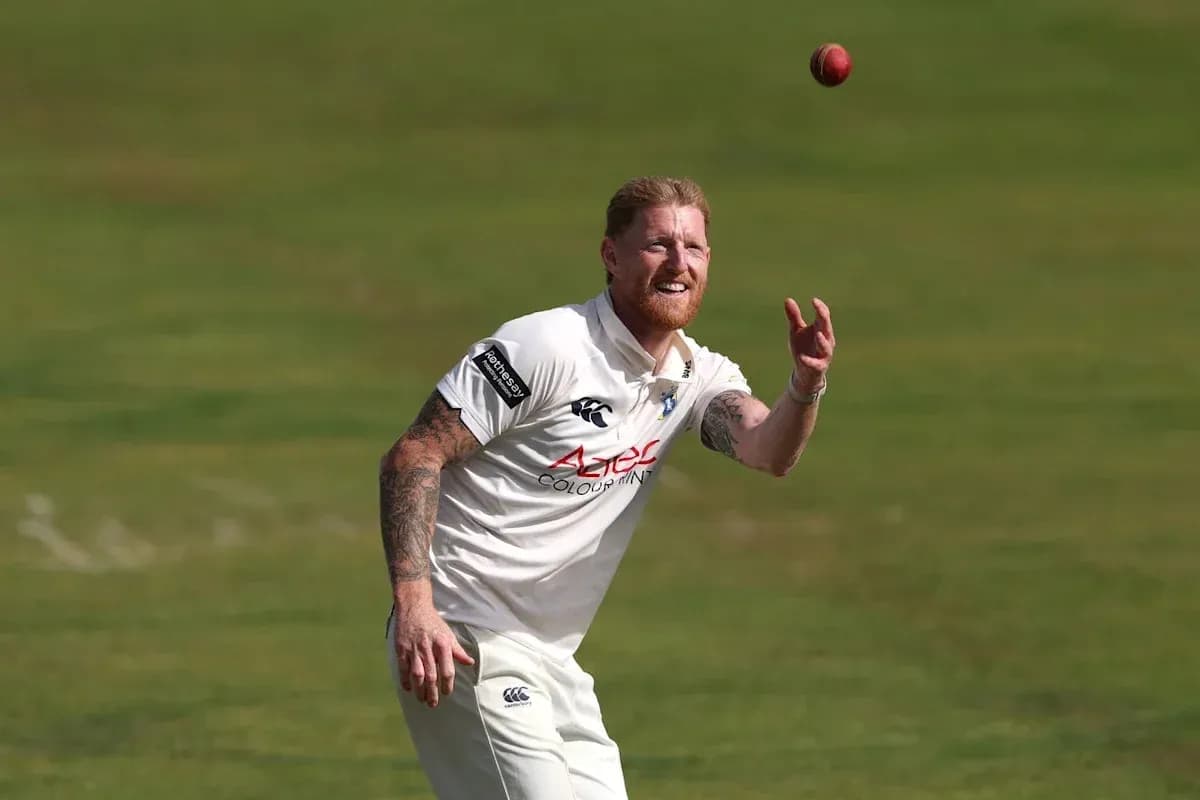 Cricketer fielding the ball on grass pitch