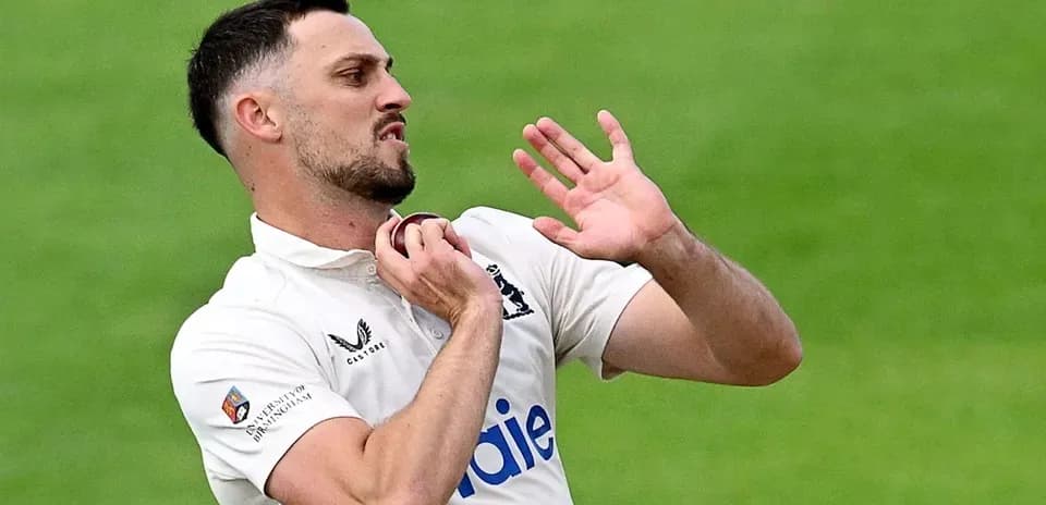 Cricketer adjusting collar during match action